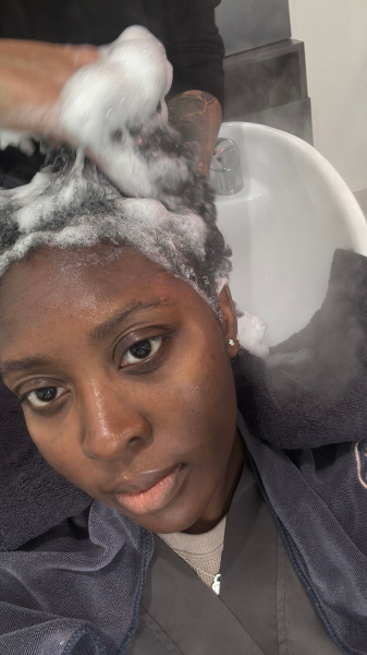 Image of Black woman getting her hair shampooed at a salon.